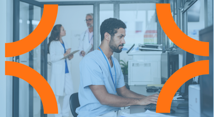 Person in scrubs working on a computer with doctors having a conversation in the background